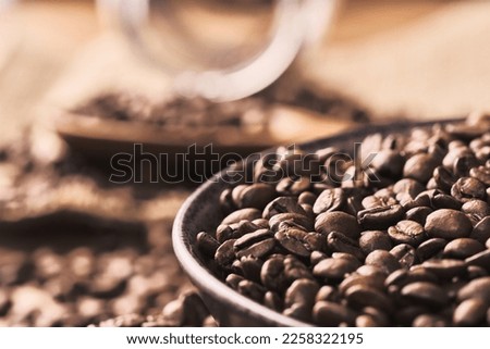 Dish of coffee beans with wooden spoon and out of glass in the bottom