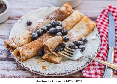 Dish With Delicious Homemade Pancakes Or Crepes Filled With Dulce De Leche. Fork With A Bite And Some Spiked Blueberries.