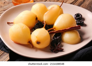 Dish with delicious poached pears, prunes, anise and cinnamon on table, closeup