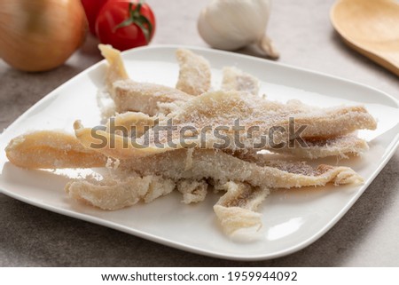 Dish with dried and salted raw cod fillets close up