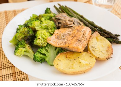 dish of fried river trout fillet with garnish of broccoli, asparagus sprouts, baked potatoes and mushroom sauce