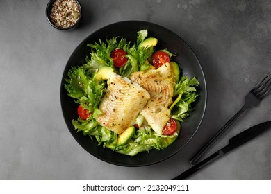 Dish With Gourmet Fried Halibut Fish On Vegetable, Fresh Green Salad. Top View. Black Plate. Fork, Knife