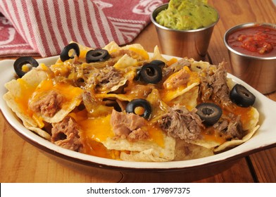 A Dish Of Nachos With Shredded Beef, Beans, Cheddar Cheese, Guacamole And Salsa