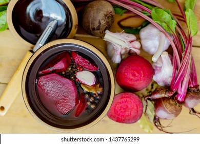 Dish with pickled beets. Rural wooden table. Preparation of borscht. Vegetables for soup. Polish cuisine. Healthy food. Beet juice. Natural treatment.