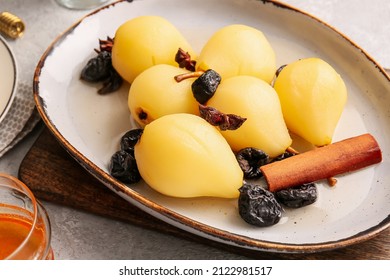 Dish with poached pears, prunes, anise and cinnamon on light table, closeup