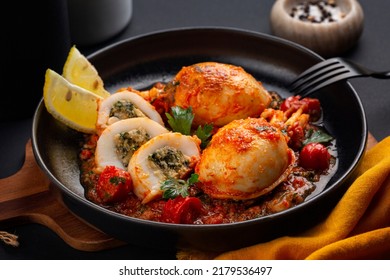 Dish with Sepia, calamari or Cuttlefish stuffed with swiss chard, bread crumbs and parmesan cheese and cooked in tomato sauce. Black background. - Shutterstock ID 2179536497
