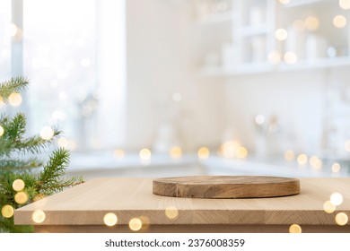 Dish serving or cutting board on wooden table in blurred kitchen with Christmas tree - Powered by Shutterstock