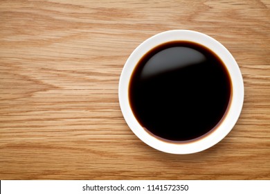 Dish Of Soy Sauce On The Wooden Table, Top View.