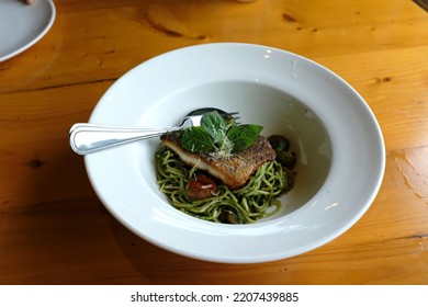 A Dish Of Spaghetti Pesto With Grilled Sea Bass Fillet On The Wooden Table.