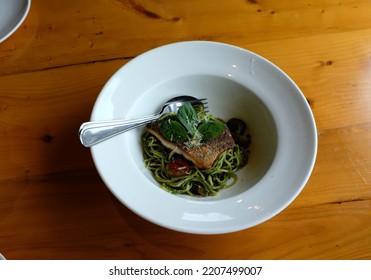 A Dish Of Spaghetti Pesto With Grilled Sea Bass Fillet On The Wooden Table.