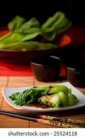 Dish Of Steamed Bok Choy With Oyster Sauce On White Plate Amid Asian Style Table Setting