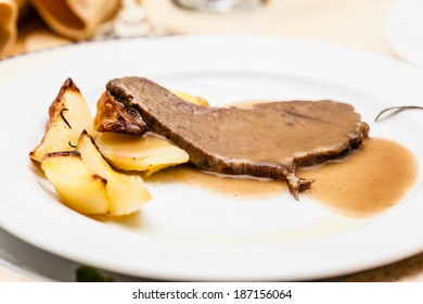 A Dish With A Thin Beef Steak And Roasted Potato Wedges