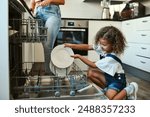 Dish washer, parent and child washing plate in home for chores, responsibility or helping hand in kitchen. Machine, care and girl in house cleaning or packing for development, learning or hygiene