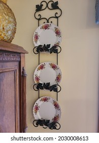 Dishes Displayed On A Wall Hanger In The Corner. The Three Fine China Plates Have A Floral Design.