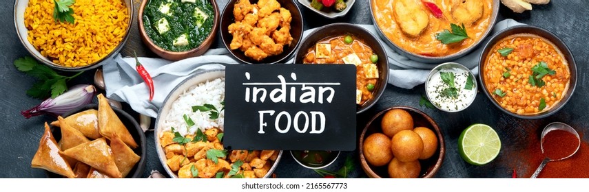 Dishes of indian cuisine. Curry, butter chicken, rice, lentils, paneer, samosa, spices. Bowls and plates with indian foodon dark on dark background. Top view, panorama.
