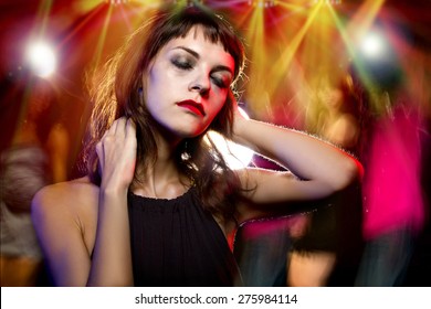 Disheveled Drunk Or Female High On Drugs At A Nightclub.  Motion Blurred Party People In The Background Dancing. 