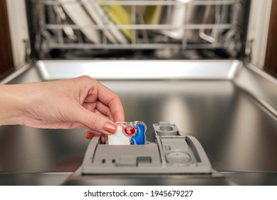 Dishwasher capsule, dishwasher tablets woman puts the capsule in the dishwasher before washing the pasta