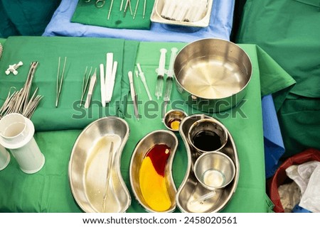 Disinfectant cup set for prepare breast surgery.Plastic surgeon sewing up breast of female patient after inserting implants in operating room.Medical team performing surgery in operation room.