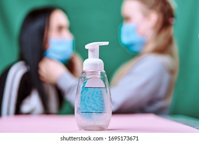 disinfectant fights bacteria. a daughter wearing a blue medical mask dresses her mom 's mask. green background pink table. covid-19. protect the health - Powered by Shutterstock