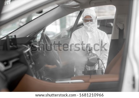 Disinfectant worker character in protective mask and suit sprays bacterial or virus in a car. Foto stock © 