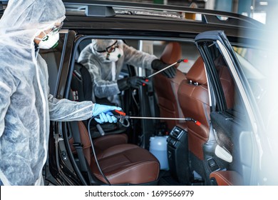 Disinfectant worker in protective masks and suits making disinfection of car seats - Shutterstock ID 1699566979