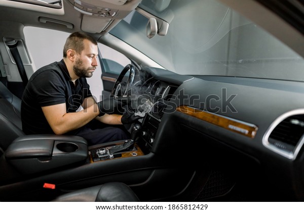 Disinfecting the car\
interior, steam heat disinfection of vehicles. Young bearded man\
worker, cleaning car air conditioner and control panel with high\
pressure hot steam\
cleaner