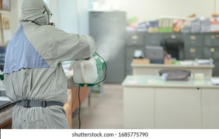 Disinfecting of office to prevent COVID-19, person in white hazmat suit with disinfect in office, Disinfectant worker wear protective mask and suit sprays coronavirus. - Shutterstock ID 1685775790