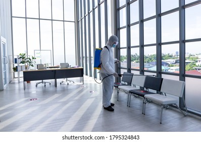 Disinfecting Public Place , Staff PPE Uniforms Suit Are Using An Alcohol Sprayer To Clean The Coronavirus In The Office To Prevent The Transmission Of COVID 19 In Hygienic Work Areas.