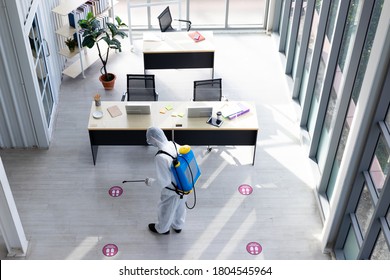 Disinfecting Public Place , Staff PPE Uniforms Suit Are Using An Alcohol Sprayer To Clean The Coronavirus In The Office To Prevent The Transmission Of COVID 19 In Hygienic Work Areas.