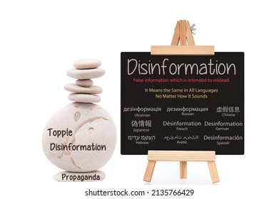 Disinformation (written In Russian, Ukrainian, Chinese, Japanese, Arabic, French, Spanish, Hebrew And German Language) Blackboard Next To Topple Disinformation Propaganda Stacked Stones