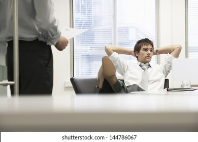 Disinterested Businessman Reclining On Chair And Ignoring Boss In Office