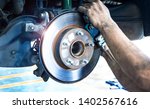 Disk brake and car disk brake system service concept - Car disk brake pad replacement service by hand of mechanic man in car garage with flare light effect and copy space