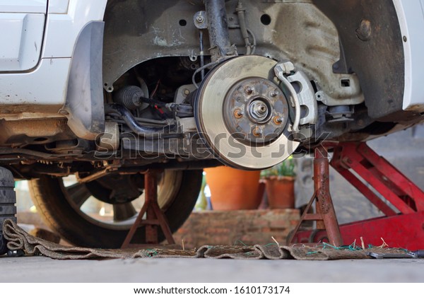 Disk brake car and car disk brake system service
concept, Disc brake of the vehicle for repair, in process of new
tire replacement. service by hand of mechanic man in car garage,
Car disk, close up.