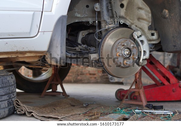 Disk brake car and car disk brake system service
concept, Disc brake of the vehicle for repair, in process of new
tire replacement. service by hand of mechanic man in car garage,
Car disk, close up.
