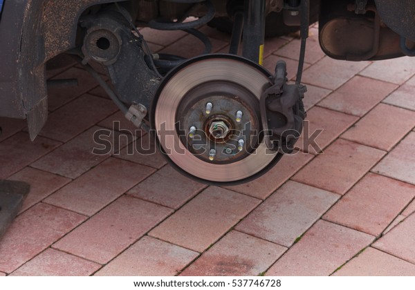 Disk brake on a car here Mechanic at\
the car brake repair in a car service\
workshop\
