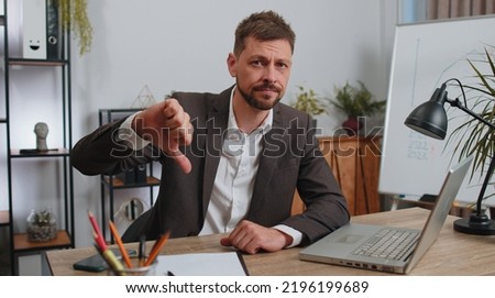 Dislike. Upset businessman in suit working on laptop computer at home office thumbs down sign gesture, expressing discontent, disapproval, dissatisfied bad work. Displeased serious male freelancer