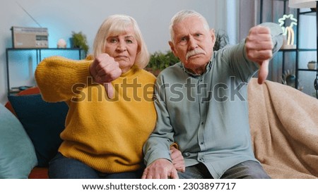 Dislike. Upset senior family grandparents man woman showing thumbs down sign, expressing discontent, disapproval, dissatisfied bad work at home. Displeased old grandmother, grandfather couple on sofa
