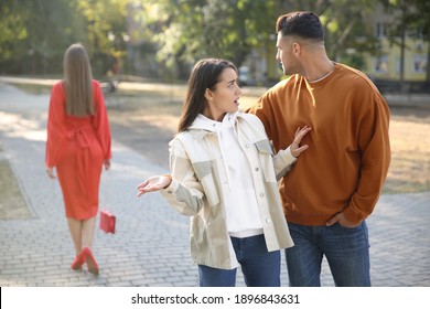 Disloyal Man Looking At Another Woman While Walking With His Girlfriend In Park