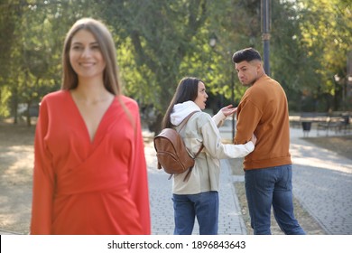 Disloyal Man Looking At Another Woman While Walking With His Girlfriend In Park