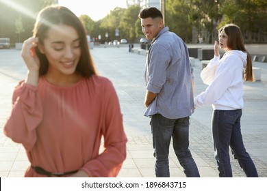 Disloyal Man Looking At Another Woman While Walking With His Girlfriend Outdoors