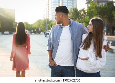 Disloyal Man Looking At Another Woman While Walking With His Girlfriend Outdoors