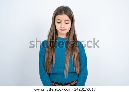 Dismal gloomy rejected beautiful kid girl wearing blue knitted sweater has problems and difficulties, curves lower lip and closes eyes in despair, being in depression