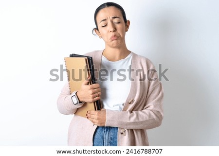 Dismal gloomy rejected Young beautiful woman holding books has problems and difficulties, curves lower lip and closes eyes in despair, being in depression