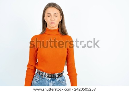 Dismal gloomy rejected Young beautiful woman standing over white studio background has problems and difficulties, curves lower lip and closes eyes in despair, being in depression