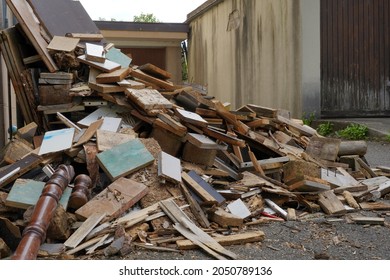 Dismantled furniture on a yard between two buildings. There are pieces of wooden furniture piled up. They are of irregular size. It looks like vacating of a dwelling.