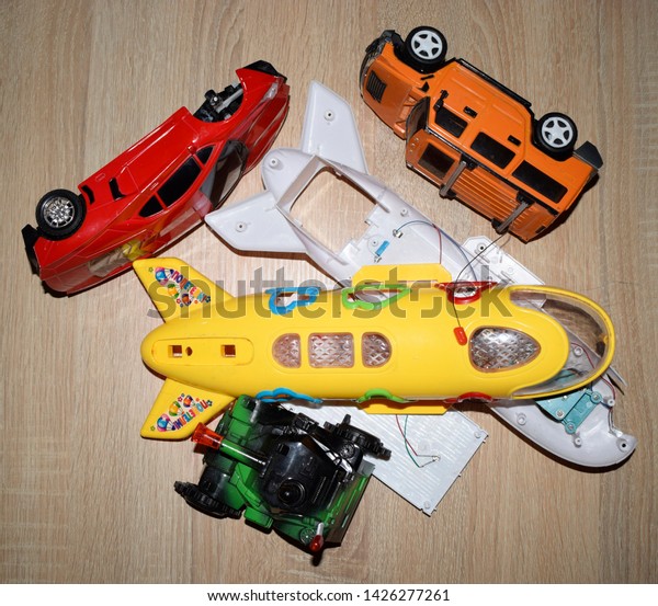 A dismantled toy cars and airplane divided in\
several pieces on wooden desk