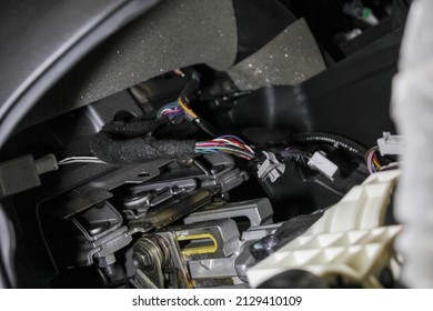 Dismantling of the car interior. Disassembled multimedia panel for repair, replacement of the multimedia system. Car wires with white connectors close-up. Repair and tuning of cars.