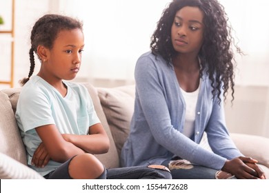 Disobedient Child. Disappointed Black Mother Looking At Her Little Daughter With Reproach, Sitting On Couch At Home