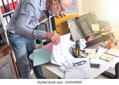 Disorganized businessman looking for documents on his desk, light effect - Shutterstock ID 676559059