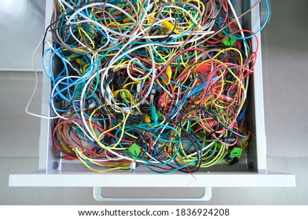 Disorganized colorful cables on a drawer. Messy wires.